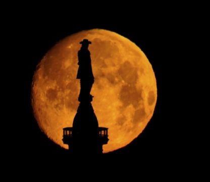 The moon sets behind a statue of William Penn atop of City Hall in Philadelphia, Wednesday, March 16, 2022.